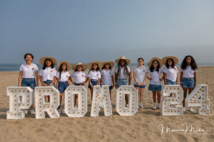 Alumnas de promoción escolar con sombreros de paja en la playa